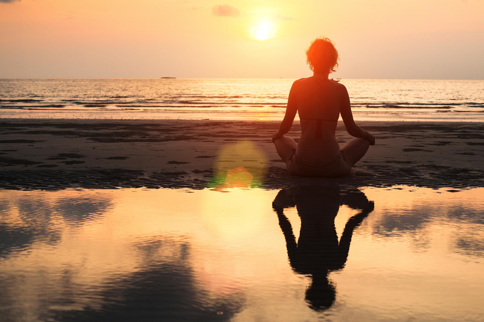 Young Woman Practicing Yoga On The Beach At Sunset. Banco de